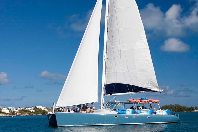 A large catamaran under full sail on blue water