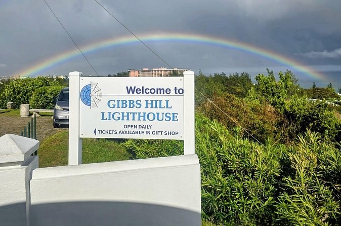 The Gibbs Hill Lighthouse welcome sign under a rainbow