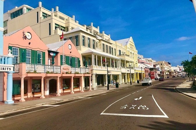 Pink and cream arcaded shopfronts along a wide harbour street