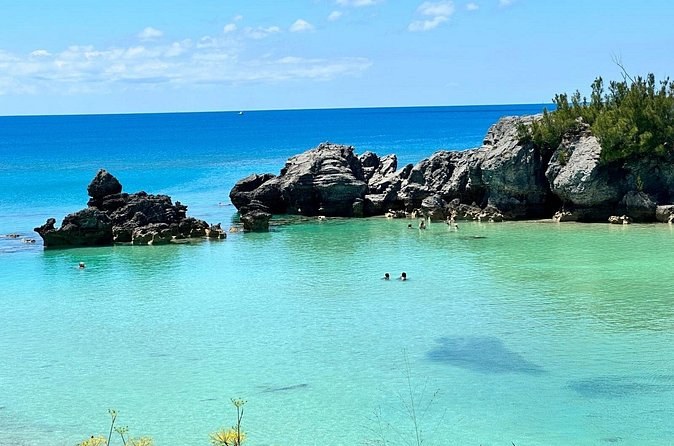 Dark rocks around a cove of clear pale-blue shallows