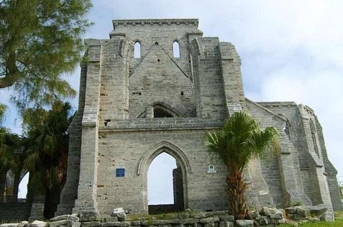 The roofless grey stone shell of a Gothic church, a palm growing beside it