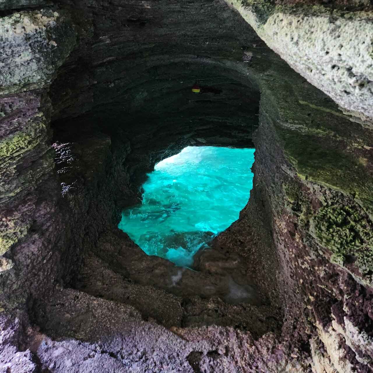 Turquoise water seen through an arch in dark limestone