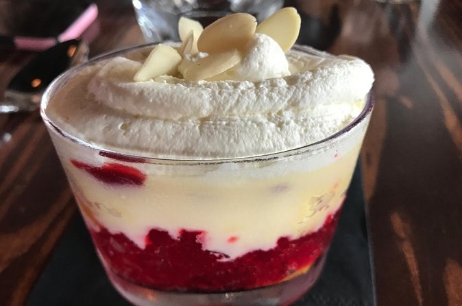 A glass of trifle with cream and sliced almonds on top