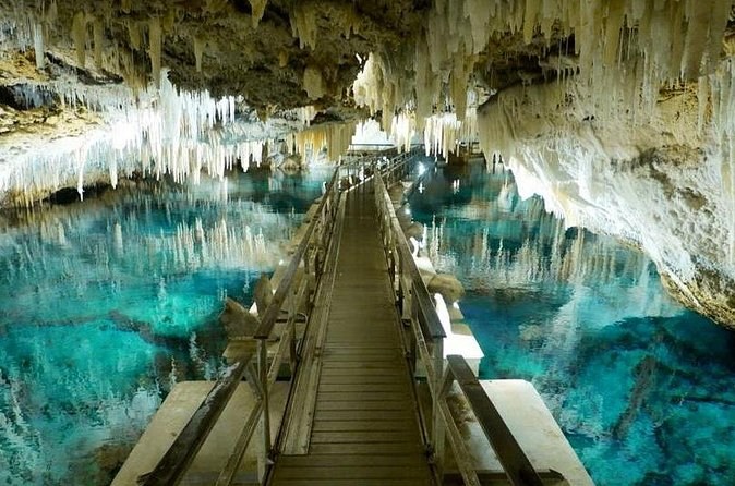 A floating wooden walkway crossing a clear cave lake under stalactites