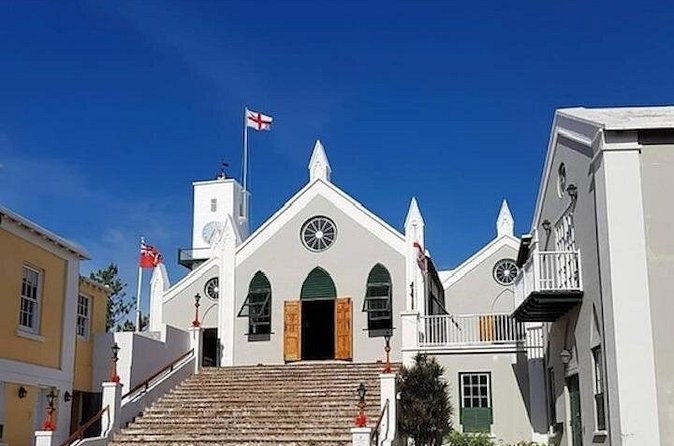 A whitewashed church with a flag above it, at the head of a flight of brick steps
